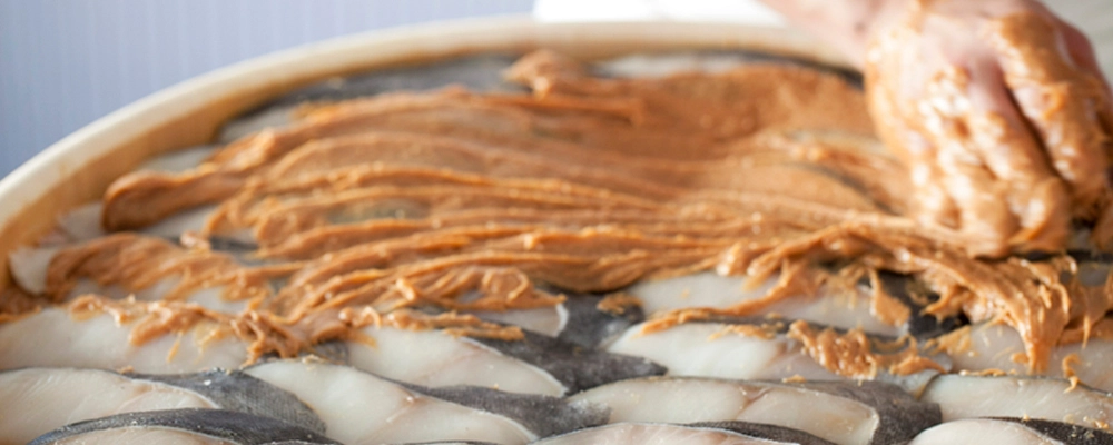 桶に並べたぎんだらを漬け込む作業の様子