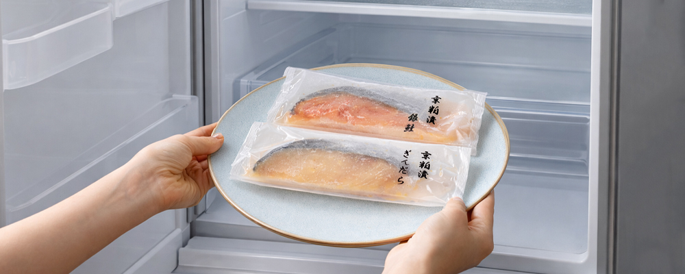 魚久の粕漬「ぎんだら」と「銀鮭」のパックを冷蔵庫に入れようとしている様子。
