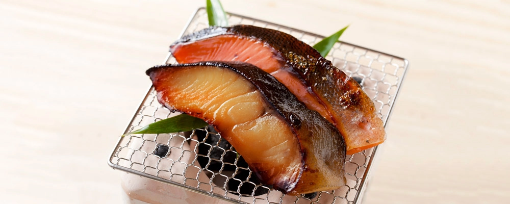 魚久 銀だらと鮭の京粕漬を七輪で焼いている調理イメージ　粕漬単品のページへ