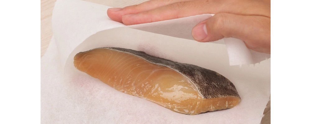 ぎんだらの粕漬けの水気をキッチンペーパーでやさしく拭き取っている様子。