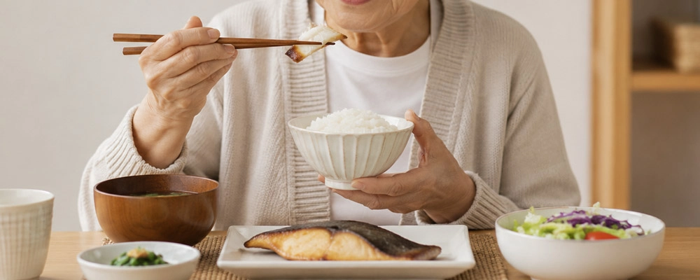 高齢の方が食卓で魚料理を食べている様子