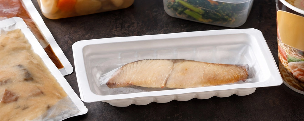 魚久の冷凍焼魚を中心に、作り置きのおかずやレトルト食品、カップ麺を並べた現代の食事準備のイメージ